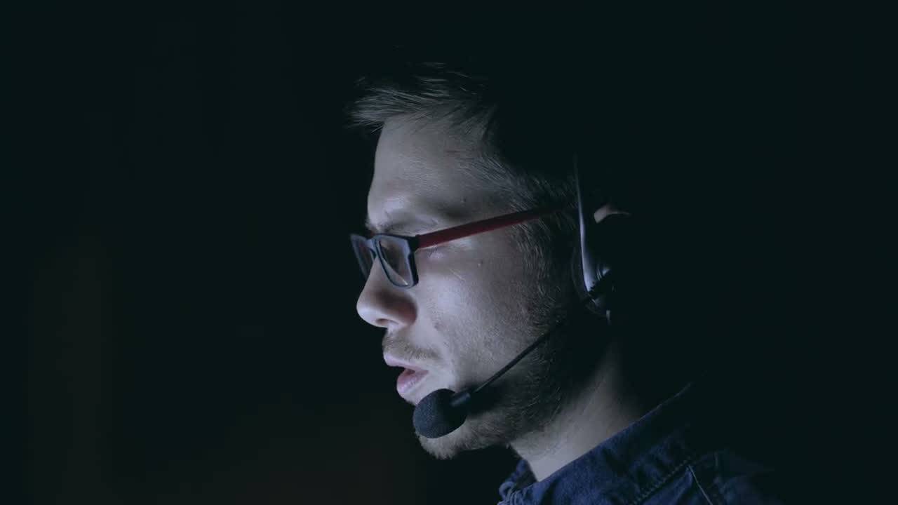 A contact center agent on a call in a dark room